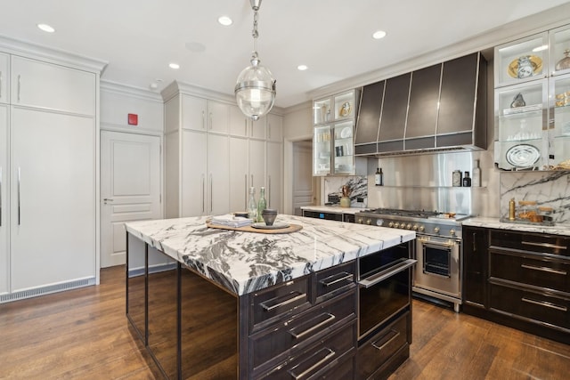 kitchen with dark wood-style floors, stainless steel stove, backsplash, glass insert cabinets, and a kitchen island