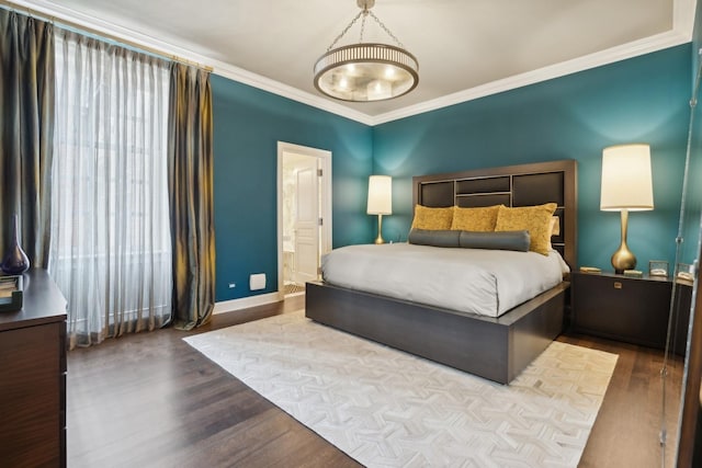 bedroom with crown molding, ensuite bath, baseboards, and wood finished floors