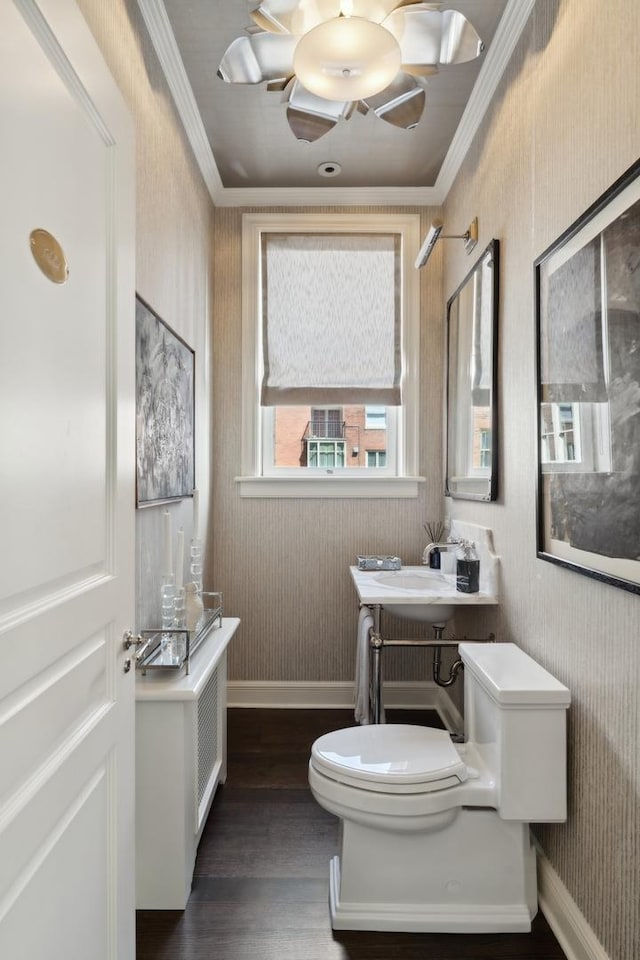 bathroom with toilet, crown molding, baseboards, and wood finished floors