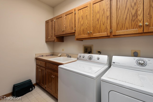 clothes washing area featuring cabinets, washing machine and clothes dryer, and sink