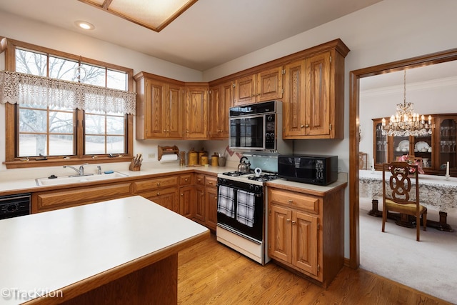 kitchen featuring pendant lighting, sink, black appliances, light hardwood / wood-style floors, and a chandelier