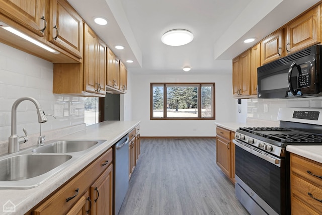 kitchen with tasteful backsplash, appliances with stainless steel finishes, sink, and light hardwood / wood-style flooring