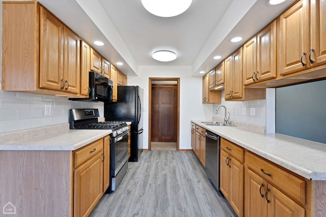 kitchen featuring light wood-type flooring, sink, tasteful backsplash, and black appliances