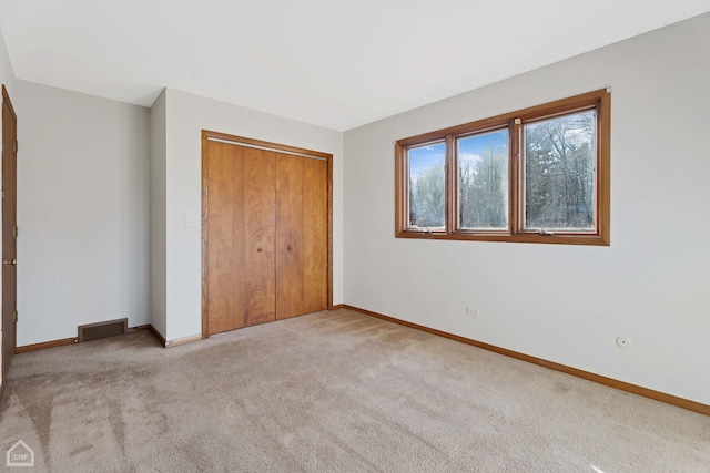 unfurnished bedroom with a closet and light carpet