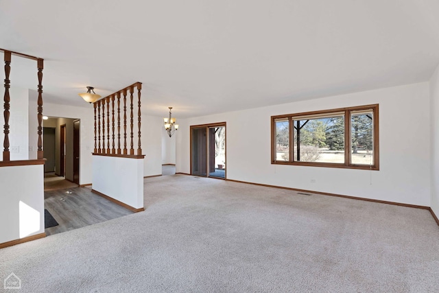 unfurnished living room featuring a chandelier and carpet