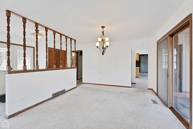 empty room featuring light carpet and a chandelier