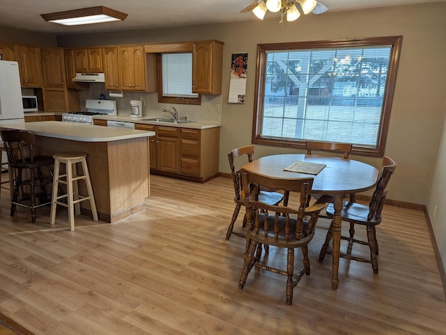 kitchen featuring a kitchen island, sink, backsplash, light hardwood / wood-style floors, and white appliances