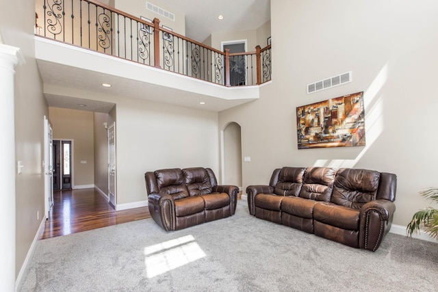 living room featuring a towering ceiling and carpet floors