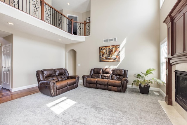 living room featuring carpet floors, a tile fireplace, and a towering ceiling