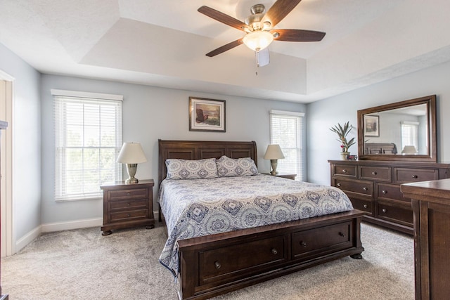 bedroom featuring light colored carpet, ceiling fan, and a tray ceiling