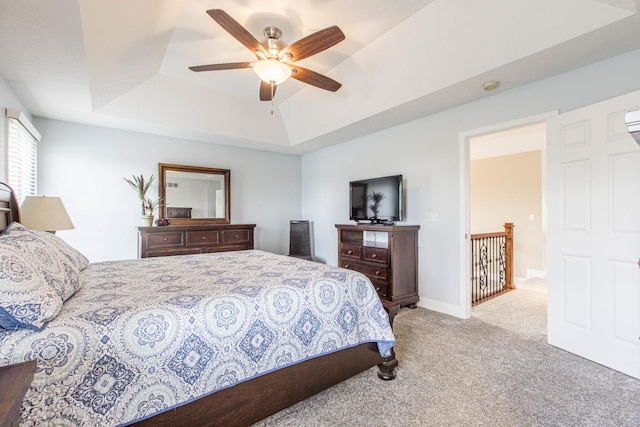 carpeted bedroom featuring a tray ceiling and ceiling fan