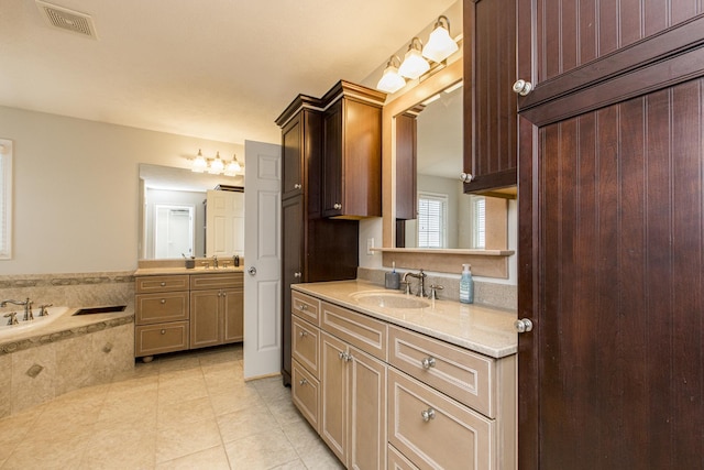 bathroom with vanity, tile patterned flooring, and tiled tub