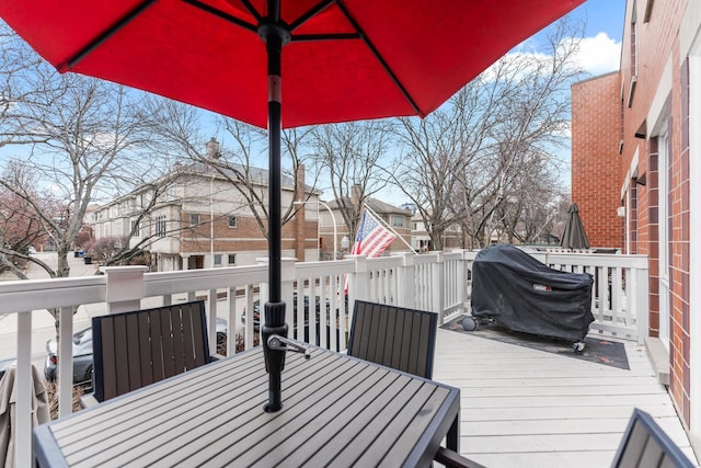 deck featuring outdoor dining area, a grill, and a residential view