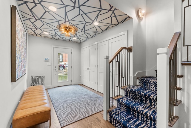 foyer entrance with stairs, wood finished floors, and baseboards