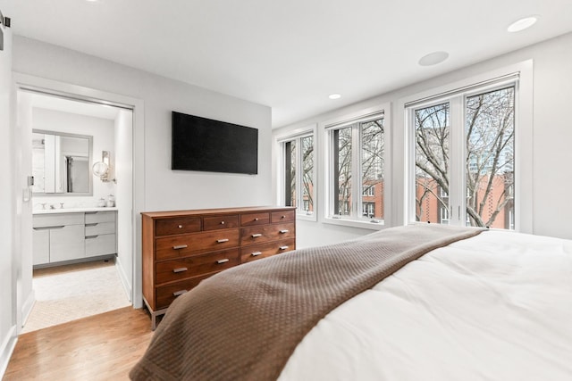 bedroom featuring recessed lighting, light wood-style flooring, a sink, ensuite bath, and baseboards