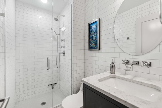 bathroom featuring tile walls, toilet, vanity, a shower stall, and backsplash