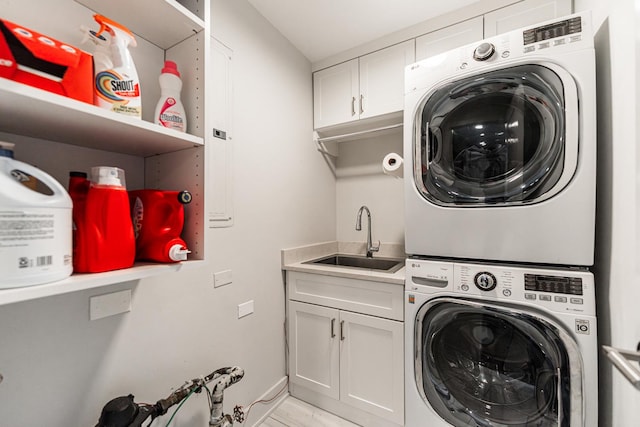 laundry area with cabinet space, a sink, and stacked washer and clothes dryer