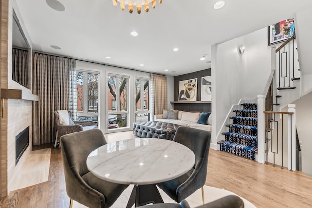 dining room featuring recessed lighting, stairway, a tiled fireplace, and wood finished floors