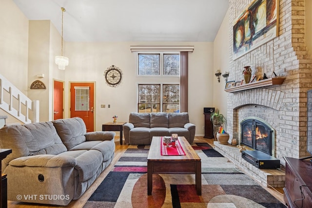 living room with high vaulted ceiling, stairs, a fireplace, and wood finished floors