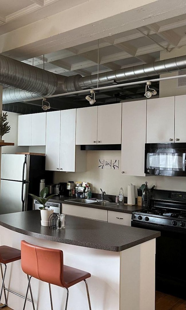 kitchen with sink, a breakfast bar area, white cabinets, and black appliances