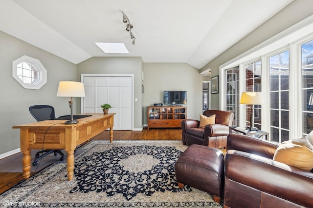 office area with vaulted ceiling with skylight, rail lighting, baseboards, and wood finished floors