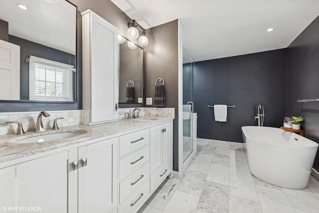 full bath with a freestanding tub, a sink, marble finish floor, and double vanity