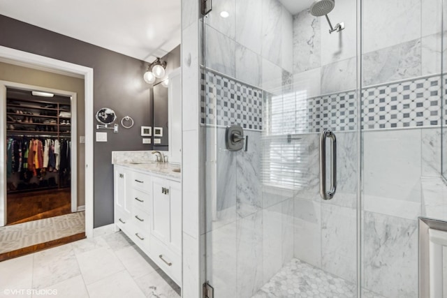 full bath featuring a stall shower, a spacious closet, and vanity