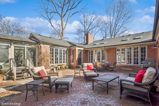 back of property with entry steps, a patio, a chimney, an outdoor living space, and brick siding