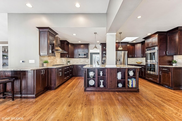 kitchen featuring a kitchen breakfast bar, light wood-style floors, appliances with stainless steel finishes, open shelves, and pendant lighting