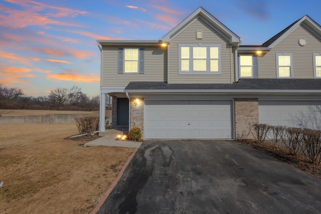 view of front of house with an attached garage, driveway, and brick siding