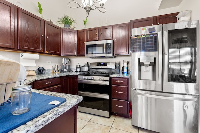 kitchen with light tile patterned floors, stainless steel appliances, dark brown cabinets, light stone countertops, and a chandelier