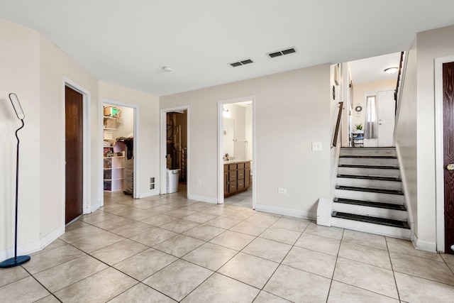 empty room with light tile patterned floors, stairway, and visible vents