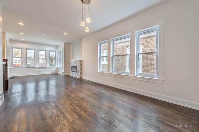 unfurnished living room featuring dark hardwood / wood-style floors and a stone fireplace