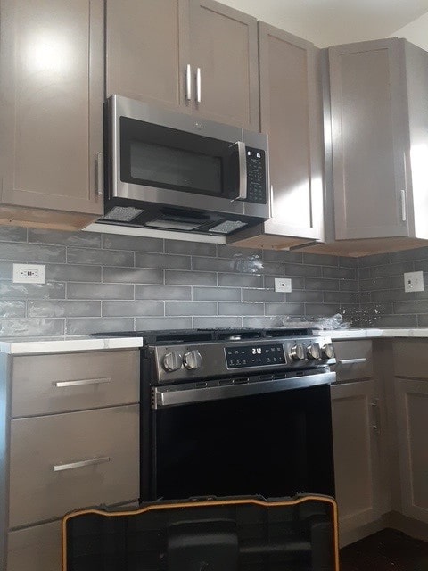 kitchen with gray cabinetry, backsplash, and appliances with stainless steel finishes