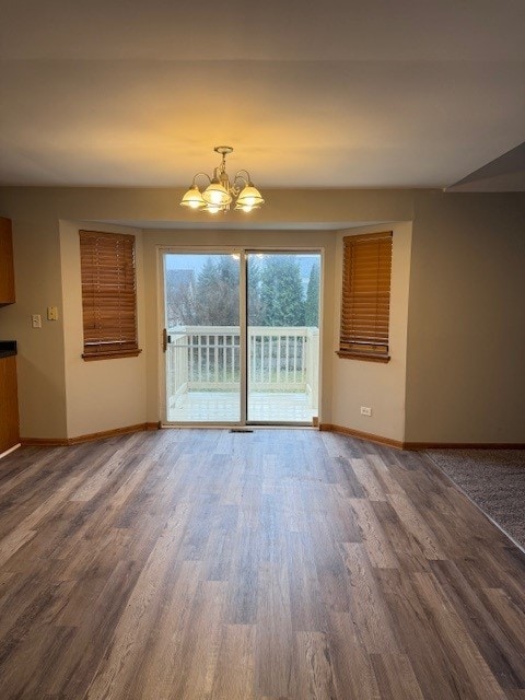 unfurnished living room with dark hardwood / wood-style flooring and a chandelier