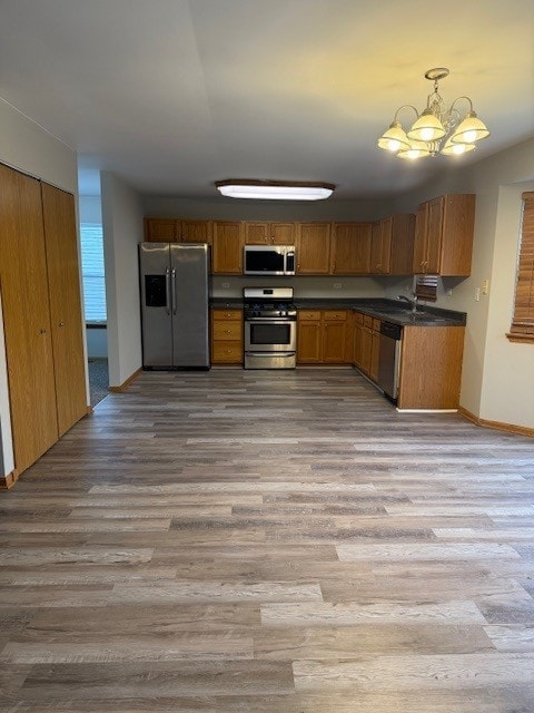 kitchen with stainless steel appliances, hanging light fixtures, light wood-type flooring, and a chandelier