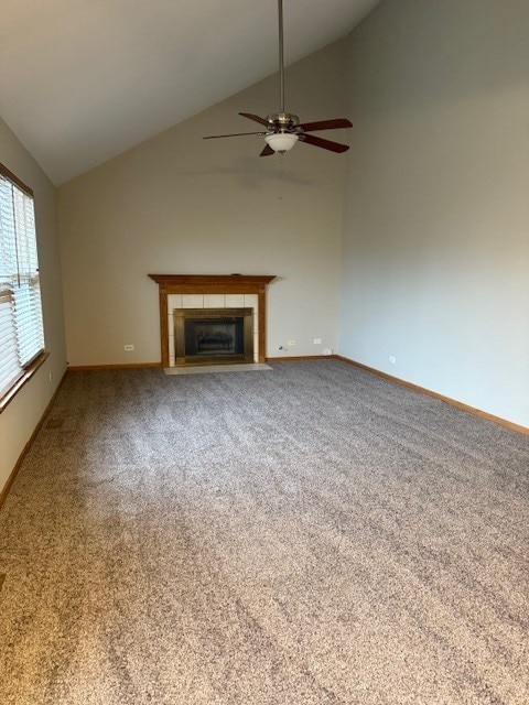 unfurnished living room with ceiling fan, a fireplace, high vaulted ceiling, and carpet