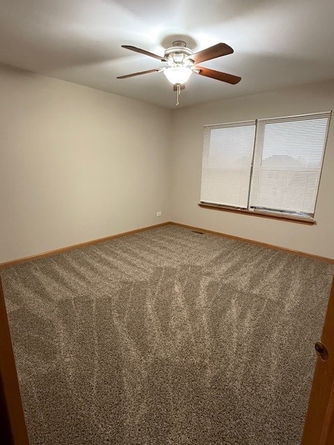 spare room featuring ceiling fan and carpet