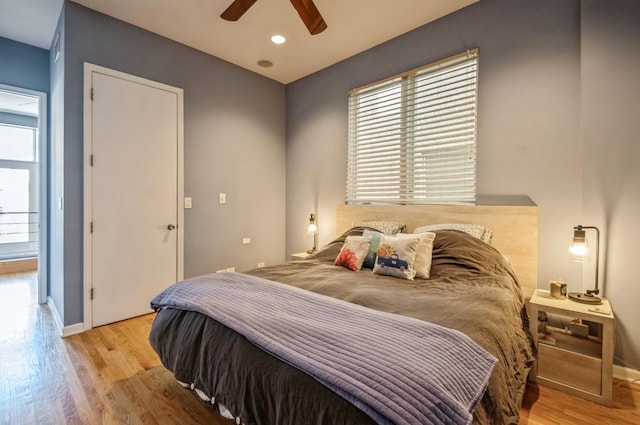 bedroom with ceiling fan, multiple windows, and light wood-type flooring