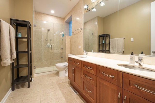 bathroom with a shower with door, vanity, tile patterned floors, and toilet