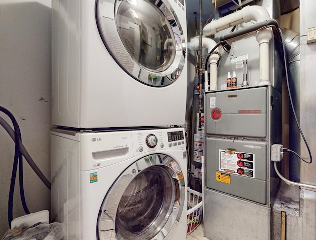 washroom featuring stacked washer and clothes dryer and heating unit