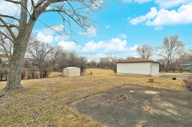 view of yard with a garage, a patio area, and a shed