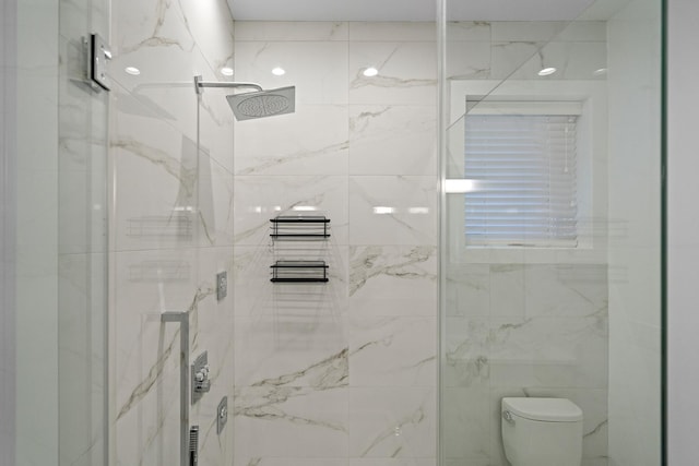 bathroom with a tile shower and toilet