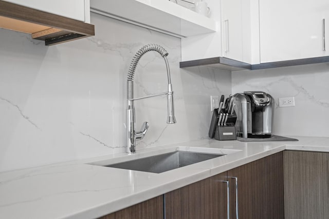 kitchen featuring white cabinetry, light stone counters, sink, and tasteful backsplash