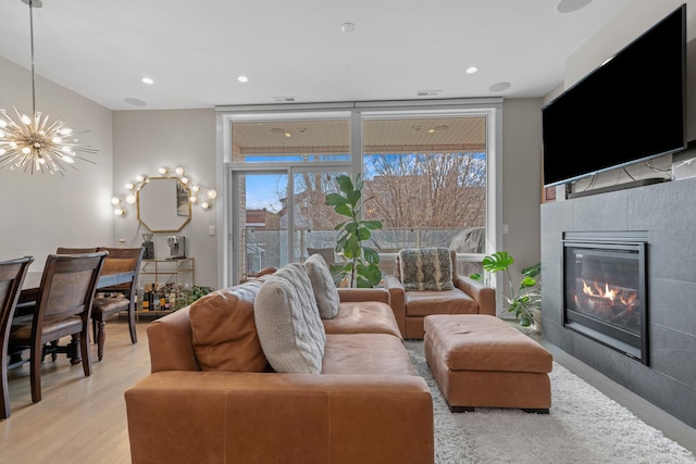 living room featuring expansive windows, a fireplace, light hardwood / wood-style floors, and a notable chandelier