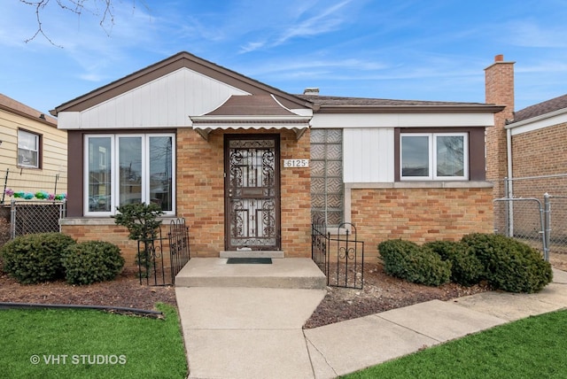 view of front facade with a gate, brick siding, and fence