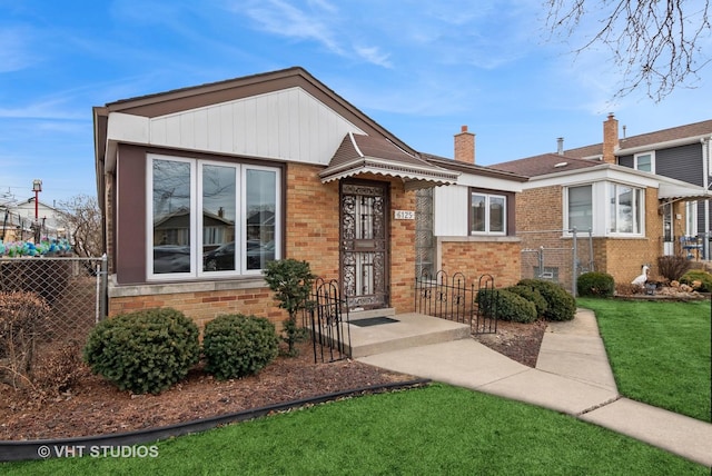 view of front of home with brick siding, fence, a chimney, and a front lawn