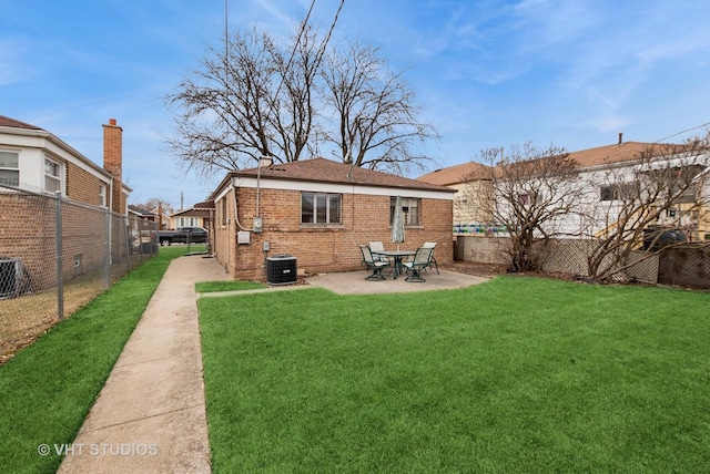 rear view of property featuring central AC unit, a fenced backyard, a yard, a patio area, and brick siding