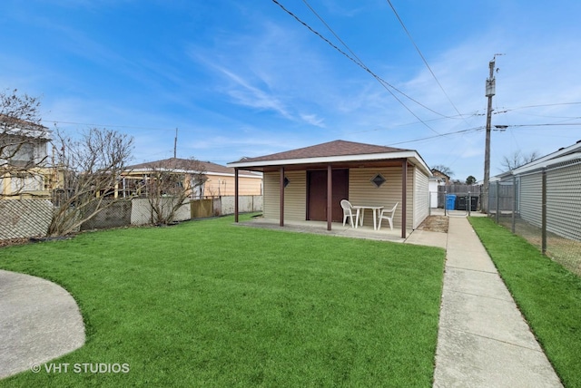 rear view of house with a fenced backyard, a shingled roof, a lawn, and a patio