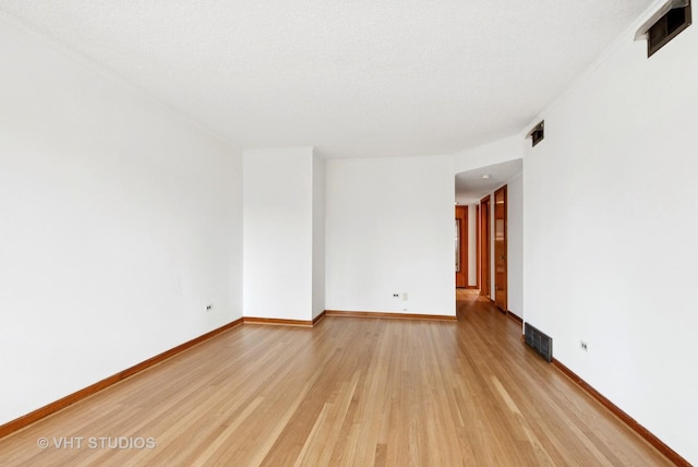 unfurnished room featuring light wood finished floors, baseboards, and visible vents